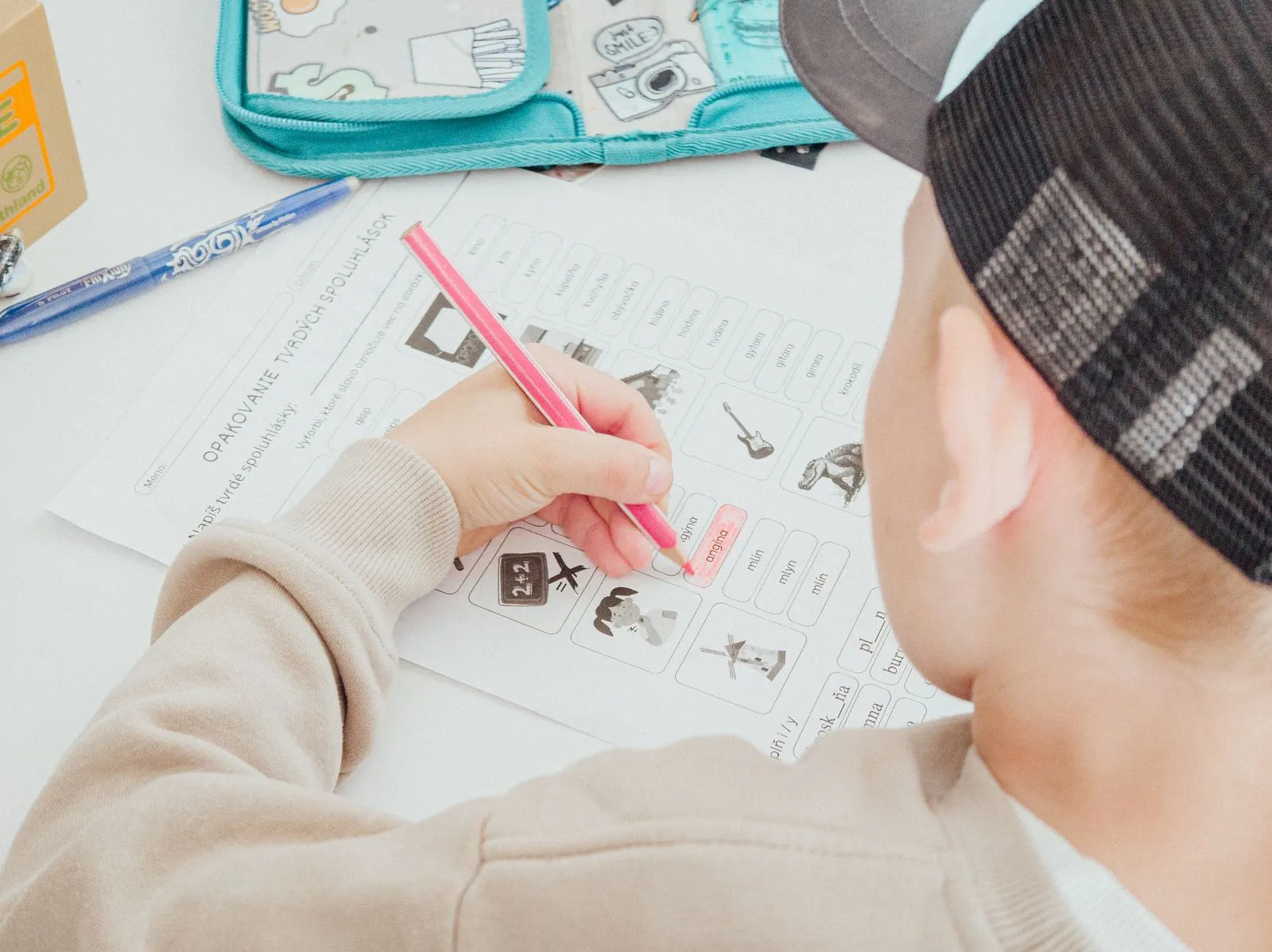 A student completing a printed math practice worksheet at a desk